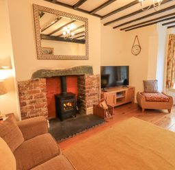 A living room with a fireplace tv armchair and window seat at Greta Mill in Keswick