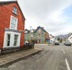 A street view with houses and parked cars on both sides under a cloudy sky at Pelham House in Keswick