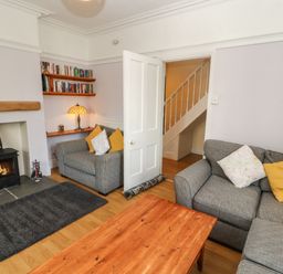 A living room with grey sofas and a wooden coffee table next to a fireplace with a wood-burning stove at Pelham House in Keswick