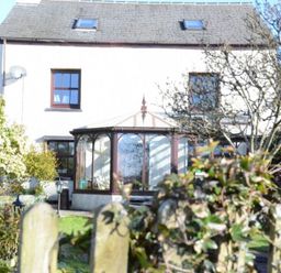 A house with a glass conservatory and garden behind a wooden fence at Greety Gate House in Foxfield