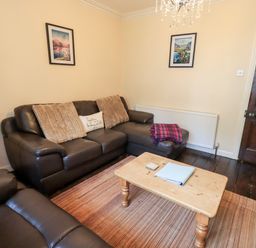 A living room with brown leather sofas a wooden coffee table and framed pictures on the wall at Walkers Rest in Windermere