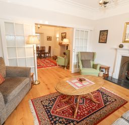 A living room with armchairs a wooden coffee table a fireplace and a patterned rug at White House in Keswick