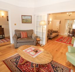 A sitting area with armchairs and a wooden coffee table on rugs with paintings on the walls at White House in Keswick