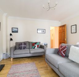 A living room with two grey sofas and colorful cushions a rug and a white heater at Siskin in Keswick