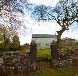 A stone wall with a gate leading to a yard with a green house a wooden shed and a stone building at Westmains Farm in Penton