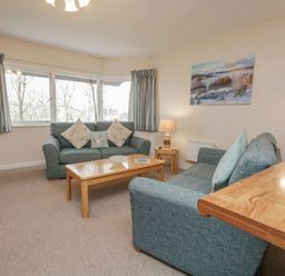A living room with two sofas and a wooden coffee table with cushions on the sofas at Treetops in Windermere