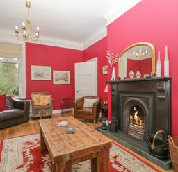 A living room with red walls a wooden coffee table and a fireplace at The Old Vicarage in Keswick