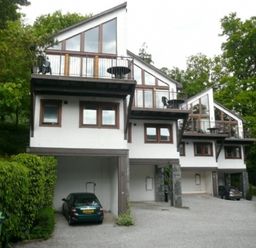 Three modern houses with covered parking and balconies surrounded by trees at 5 Keswick Bridge in Keswick