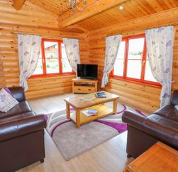 A sitting room with two leather sofas a coffee table a television and floral curtains at Willow Lodge in Greetham Rutland