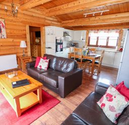 A living room and kitchen area with brown leather sofas and wooden dining table at Church View in Greetham Rutland