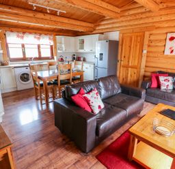 A living room and kitchen with wooden furniture and leather sofas at Church View in Greetham Rutland