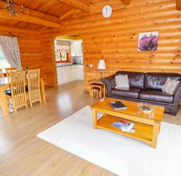 A living room and dining area with wooden furniture and log walls at Beech Lodge in Greetham Rutland