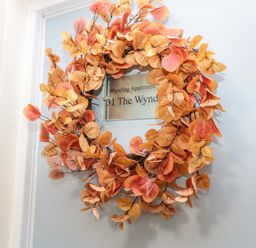 A door with an autumn leaf wreath and a sign reading Wynding Apartment at Wynding Apartment in Amble-By-The-Sea