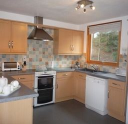 A kitchen with wooden cabinets appliances and a window at 20 Keswick Bridge in Keswick