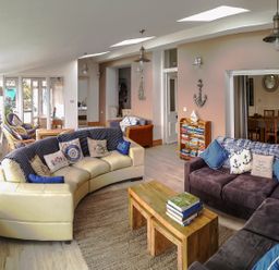 A living room with two sofas a wooden coffee table a small bookshelf and dining area at Angorfa in Cemaes Bay