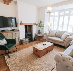 A living room with a sofa, armchair, and television at Harriet's Cottage in Briggswath