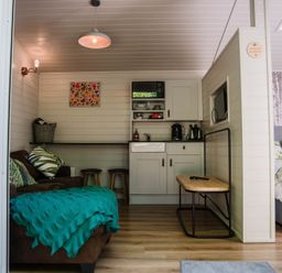 A living room with a sofa and kitchenette at Reflection in Longtown
