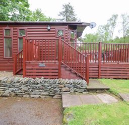 A wooden cabin with a fenced deck and stone wall at 10 Thirlmere White Cross Bay near Troutbeck Bridge
