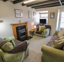 A living room with a fireplace two armchairs a sofa a television and framed pictures on the walls at Ty Uchaf in Dyffryn Ardudwy