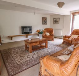A living room with brown leather sofas a wooden coffee table and a television at The Barn in Abergavenny
