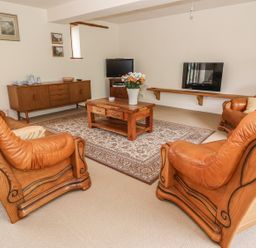 A living room with leather armchairs a wooden coffee table and a sideboard at The Barn in Abergavenny