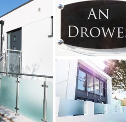 The exterior of a modern building with glass and metal railings and a sign that reads An Drowes in Newquay