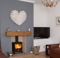 A living room with a fireplace television leather sofas and wall art at Seashell Cottage in Amble-By-The-Sea