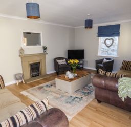 A living room with sofas a coffee table a fireplace and a television at Oakdene in Neyland