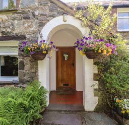 An exterior entrance with a door and hanging baskets at Plas Mawr in Groeslon