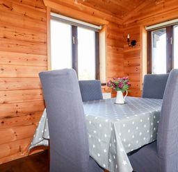 A dining area with a table covered with a star patterned tablecloth and four chairs in a wooden room at Willow Lodge Lanivet near Bodmin