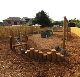 An outdoor play area with play equipment and wood chip surface at Hazel Lodge near Bodmin
