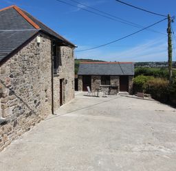 A stone building with slate roof and small patio area with table and chairs at Sunnywell Lanivet near Bodmin
