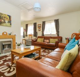 A living room with brown leather sofas a wooden coffee table and a fireplace at Richmond Cottage in Burythorpe near Malton