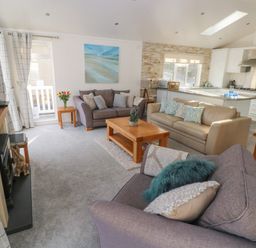 A living room with sofas coffee table and television next to an open kitchen at The Lookout in Stepaside