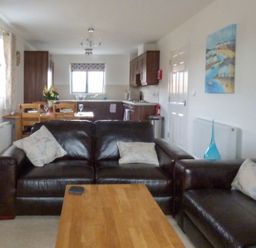 A living room with leather sofas and cushions a wooden coffee table and a dining table with chairs and flowers at Tyack in Charlestown