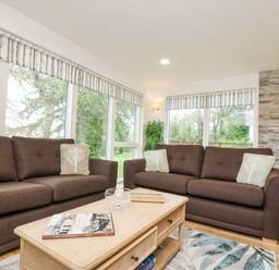 A living room with brown sofas a wooden coffee table and a fireplace at Birch in Truro