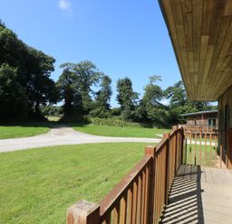 A wooden deck overlooking a grassy area with a gravel path and trees at Birch in Truro