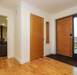 An entrance hallway with wooden doors a mirror a potted plant and visible adjoining living room at Juniper in Truro