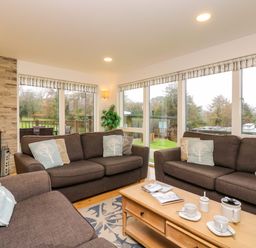 A living room with brown sofas, cushions, a wooden coffee table, and a fireplace at Juniper in Truro