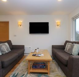 A living room with two sofas facing a wall mounted TV and a wooden coffee table in between at Oak in Truro