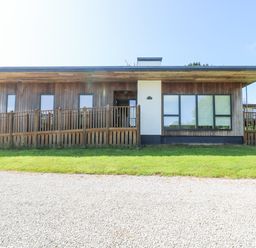 A single story wooden house with multiple windows and a fenced ramp at Willow in Truro