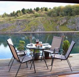 A balcony with a table and chairs overlooking a water body at Boavista in Carnforth
