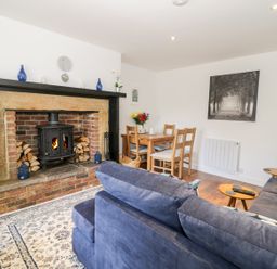 A living room with a wood burning stove fireplace a blue sofa a wooden dining table and chairs at Skovhaven in Catton