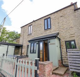A stone exterior house with green painted porch and picket fence at Skovhaven in Catton