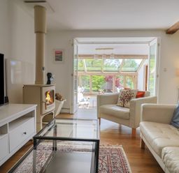 A living room with a wood stove and glass door to the garden at Pottery Barn in Branscombe