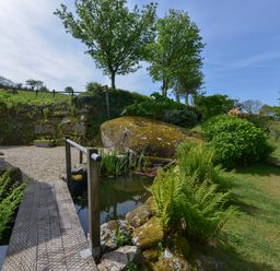 A garden area with a small bridge over a pond surrounded by greenery at Buster Barn in Sampford Spiney near Tavistock