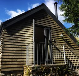 A wooden exterior cabin with a small balcony and metal railing at The Linhay in Lydford