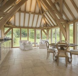 A kitchen dining area with wooden beams large windows and doors two armchairs and a round dining table with four chairs at Cullaford Cottage Scorriton near Ashburton