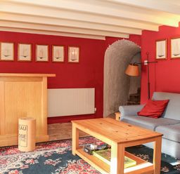 A living room with a wooden coffee table gray sofa and red walls at Sandridge Barton in Stoke Gabriel