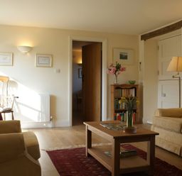 A living room with a sofa, armchair, coffee table, and bookshelf at The Barn in Compton Bishop, near Cheddar